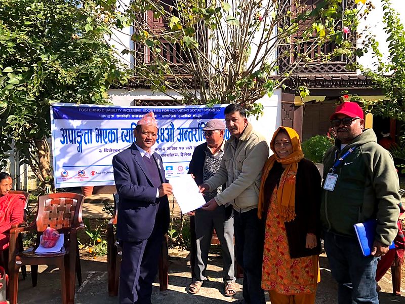 PDDF representatives handing a memorandum to an official in front of a banner for the International Day of Persons with Disabilities