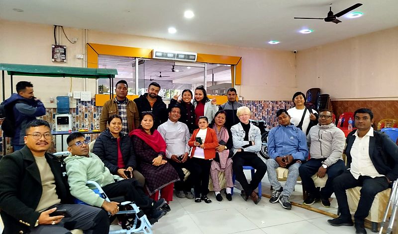 PDDF members and partners, including a wheelchair user and people using crutches, gathered together for a group photo