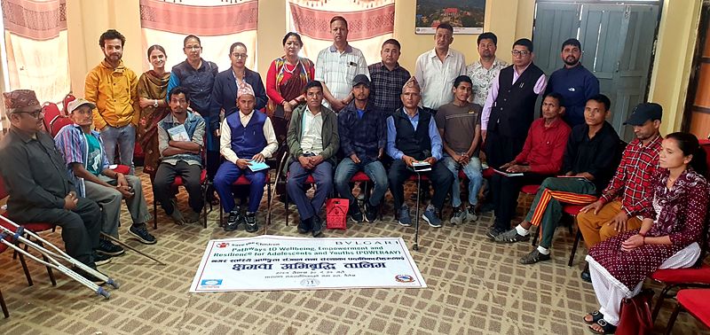 Participants of a POWER4AY capacity development training, some using crutches and walking sticks, seated behind a Save the Children banner
